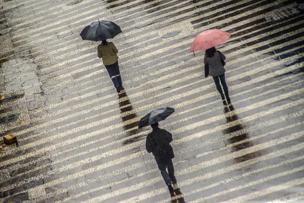 Pedestres se protegem do frio e da chuva no centro histórico da cidade de São Paulo. — Foto: CRIS FAGA/ESTADÃO
